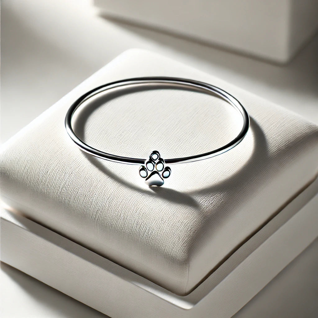 Bracelet en argent avec un charm en forme de patte de chat, exposé sur un support blanc élégant, design sobre et moderne