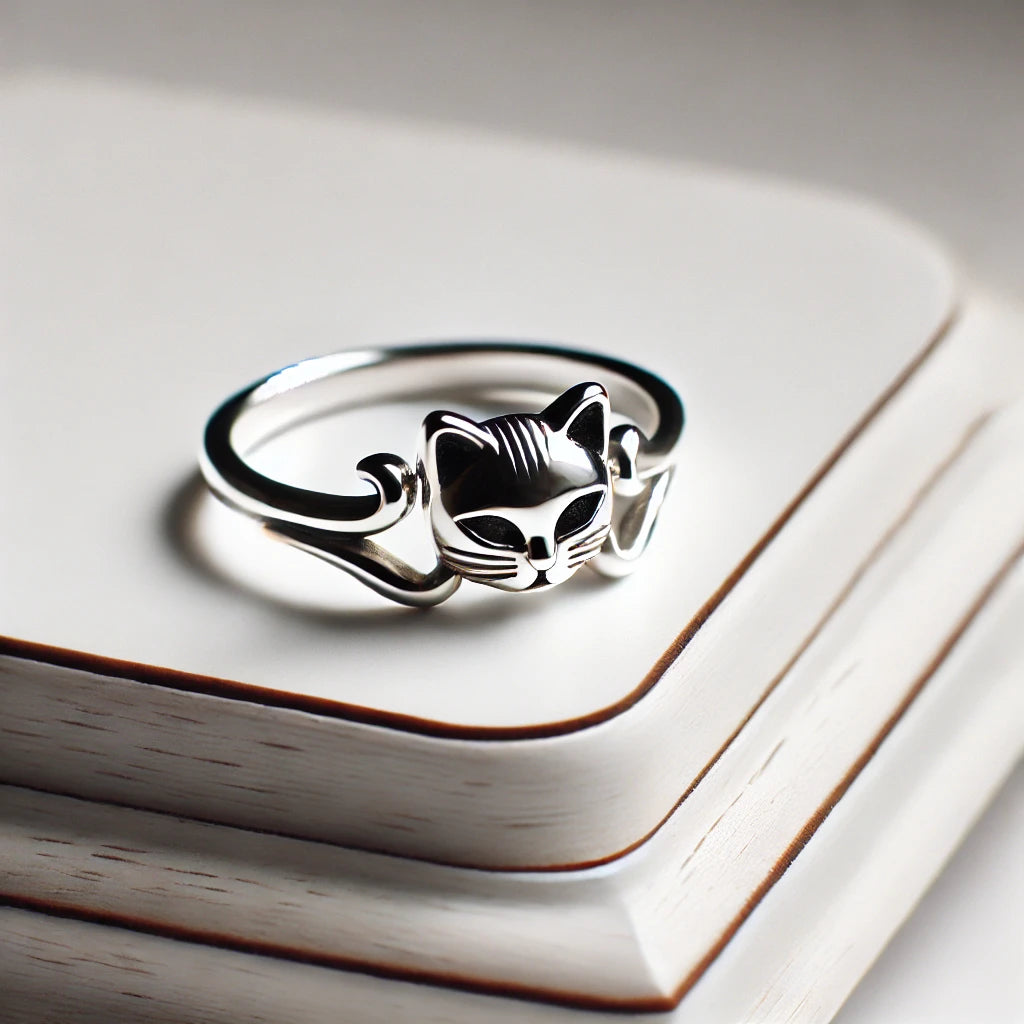 Bague en argent représentant un chat enroulé autour du doigt, affichée sur un support élégant avec un fond blanc